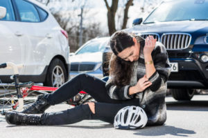 Injured biker at the street from car accident.