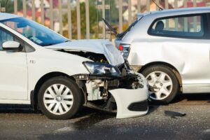 Two silver cars in rear-end accident in the road.