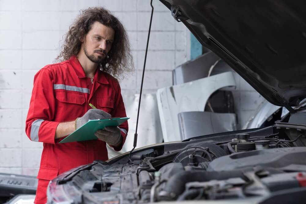 Vehicle inspector checking car for maintenance.