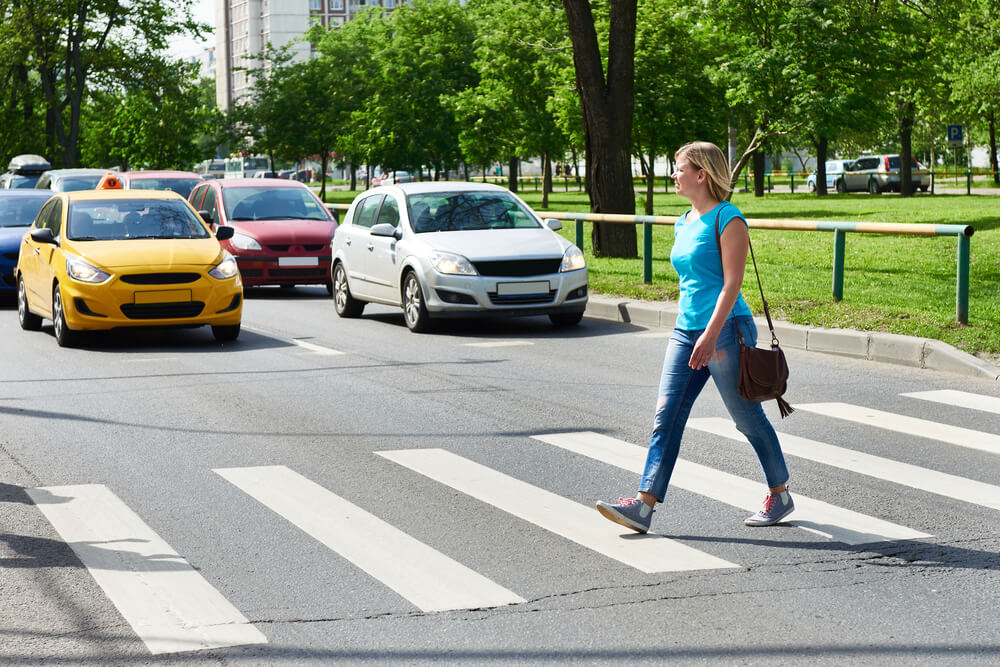 Lady crossing lane while cars stopped.